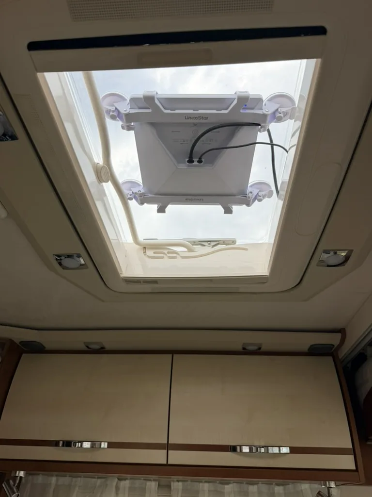 Starlink in einer abnehmbaren Saugnapfhalterung am Dachfenster des Wohnmobils